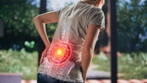 Person outdoors with a translucent spine overlaid on the back, highlighting lower back pain area.