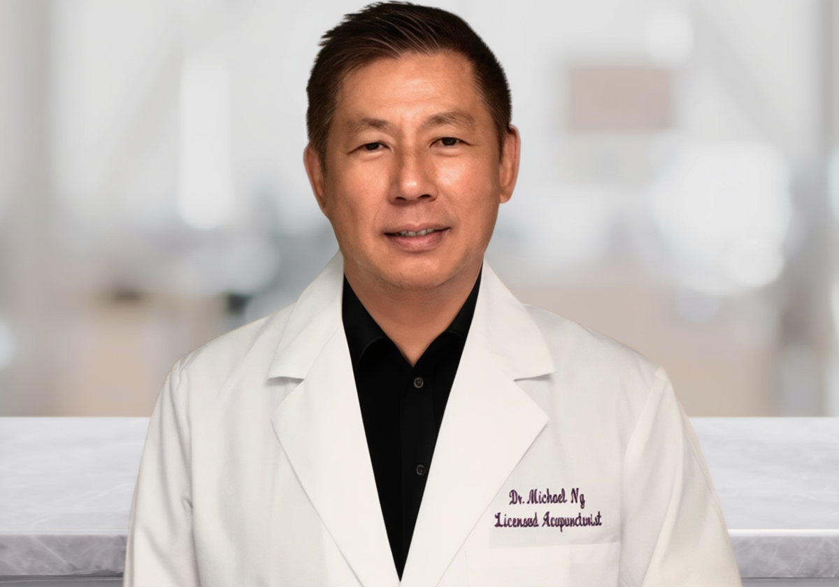 Dr. Michael Ng, licensed acupuncturist, in a white coat, smiling in a clinical setting.